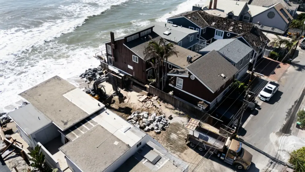 Heavy equipment moves boulders into place to protect homes along...