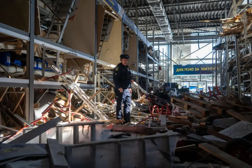 A police officer inspects a commercial facility damaged in a Russian drone attack.