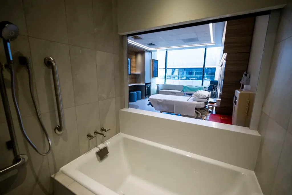 A birthing suite with a deep tub with a privacy...