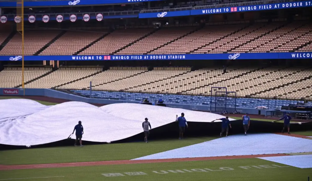 The Dodgers grounds crew pulls the tarp onto the field...