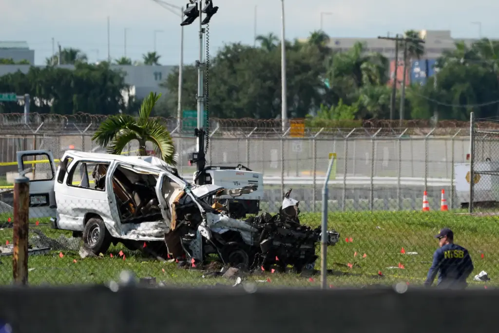 An NTSB investigator works near a damaged van at the...