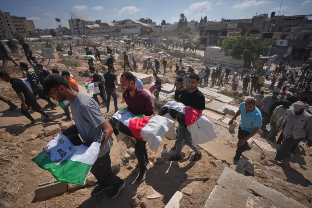 Mourners carry the flag-draped bodies of Palestinians killed in Israeli...