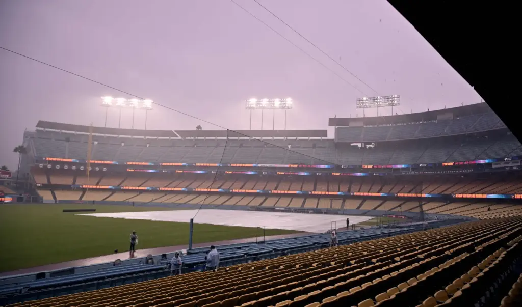 Dodgers security officers stand on the field in the rain...
