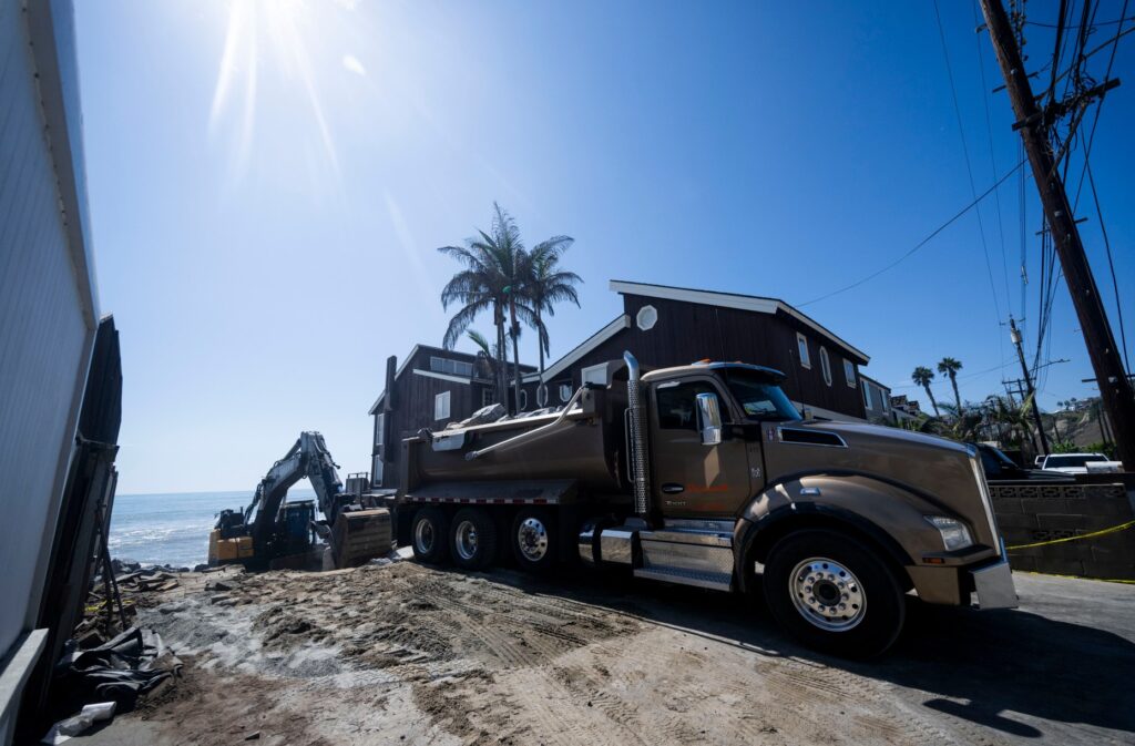 Heavy equipment moves boulders into place to protect homes along...