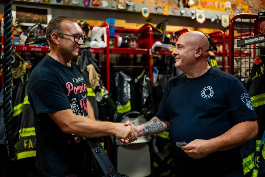 Firefighter Sal Argano, right, Ladder 10, greets Laurent Cosenefroy.