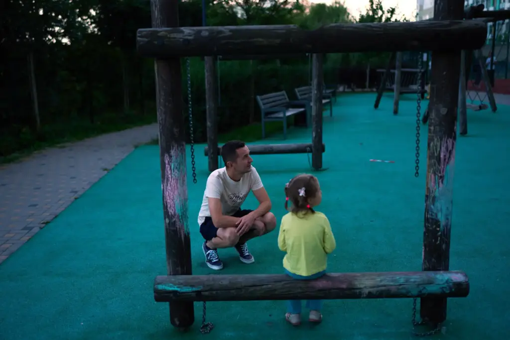 Volodymyr Bovsunovskyi talks to his daughter at the playground of their residential complex.