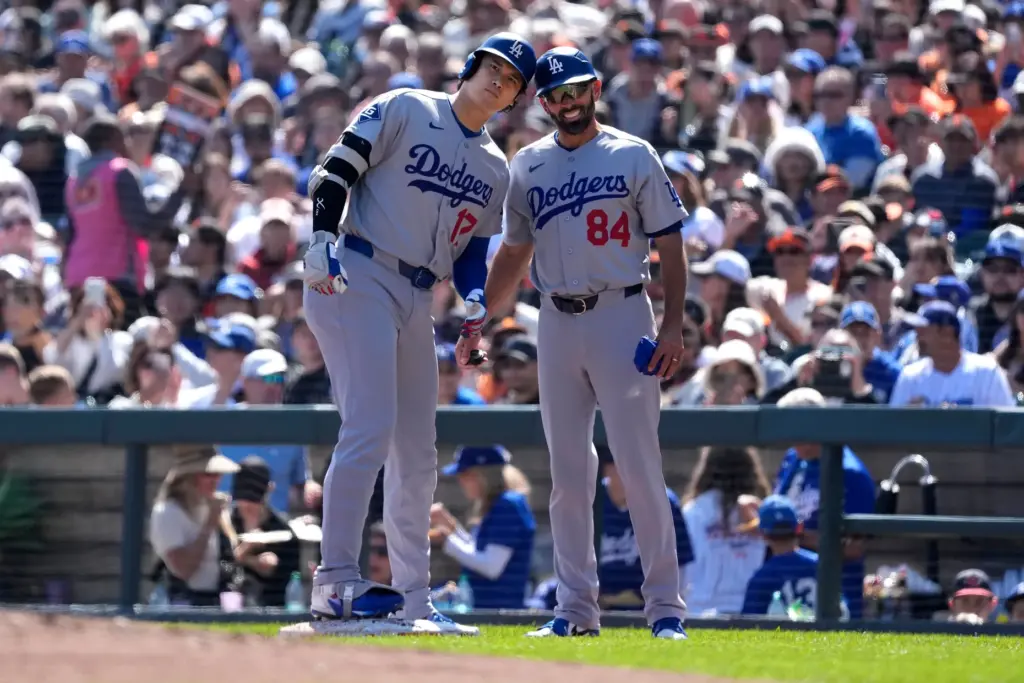 Dodgers’ Shohei Ohtani, left, is congratulated by first base coach...