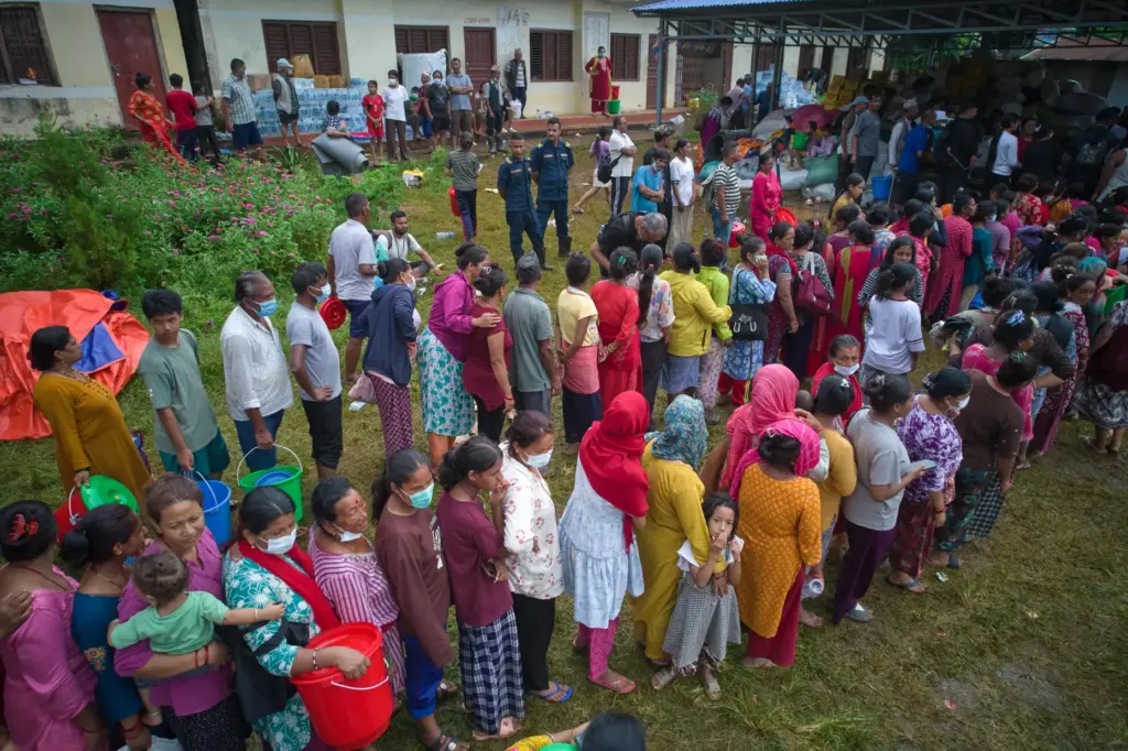 People affected by recent flash floods stand in line to receive aid.