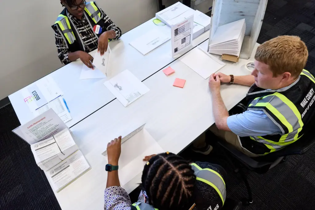 Wake County Board of Elections employees prepare absentee ballots to...