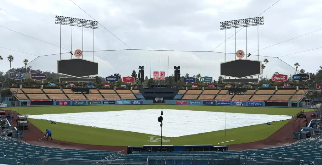The tarp covers the field as rain falls before the...