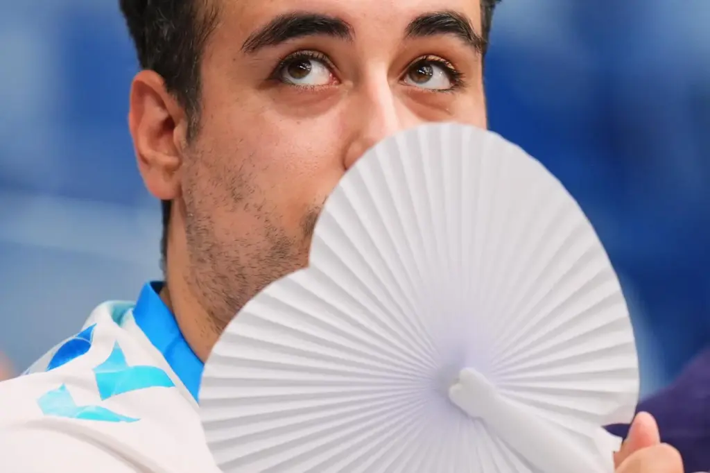 A man uses a fan to cool off during a La Liga soccer match.