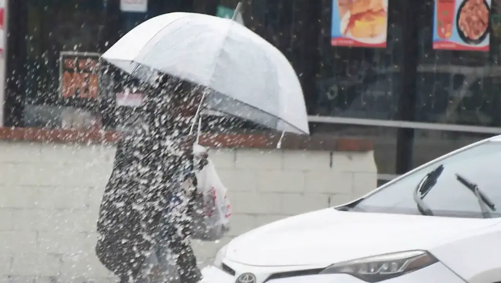 A women gets hit by water from drivers driving through...