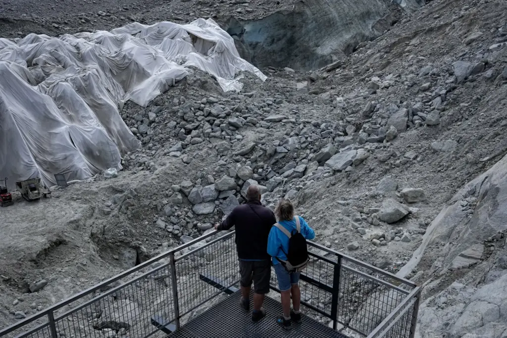 People look at the Mer de Glace glacier as tarpaulins cover the ice cave.