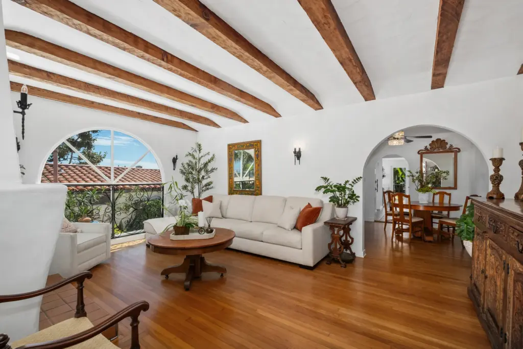Inside, the main living area features white walls, warm hardwood...