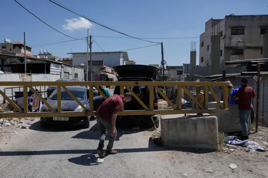 Palestinian men cross a closed gate.