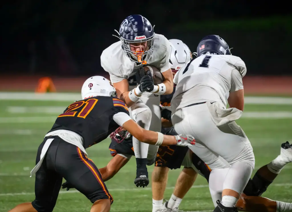 Trabuco Hills running back Luke Hoffman, center, tries to get...