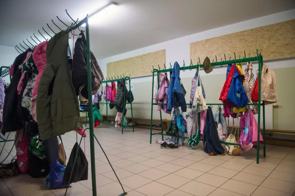 Children’s jackets and bags hang on racks inside a school...
