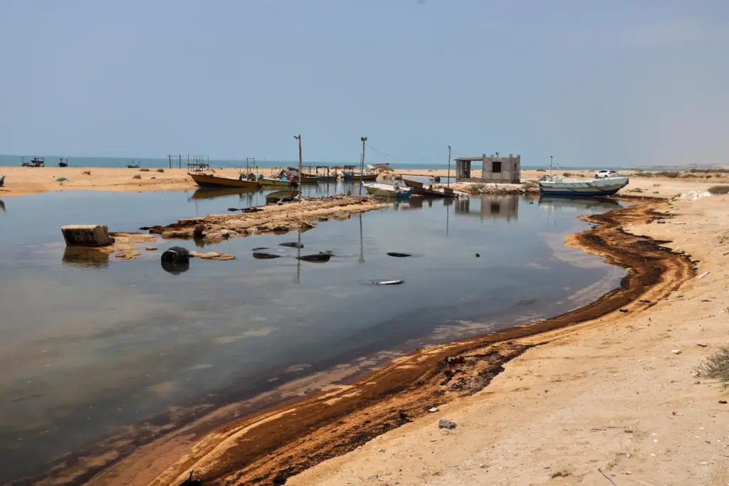 Oil residue lines the shore near fishing boats on Qeshm Island, Iran.