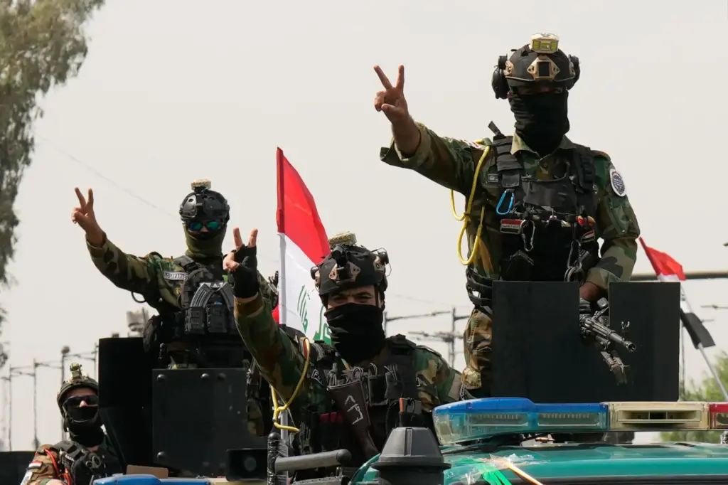 Iraqi security officers flash victory signs while riding in vehicles decorated with national flags.