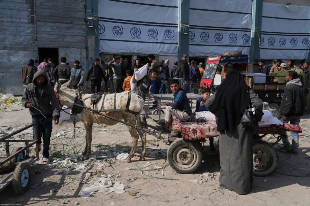 FILE – Palestinians receive bags of flour and other humanitarian...