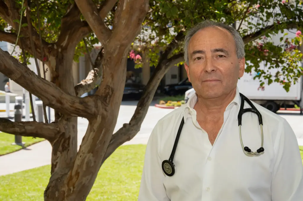 Dr. Steven M. Taback, M.D., stands beside a tree planted...