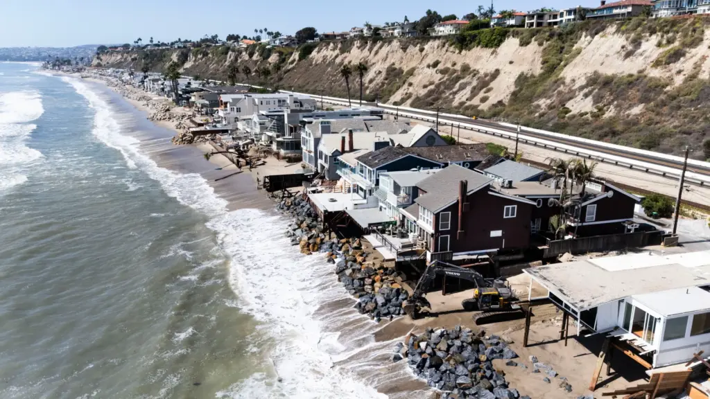 Heavy equipment moves boulders into place to protect homes along...