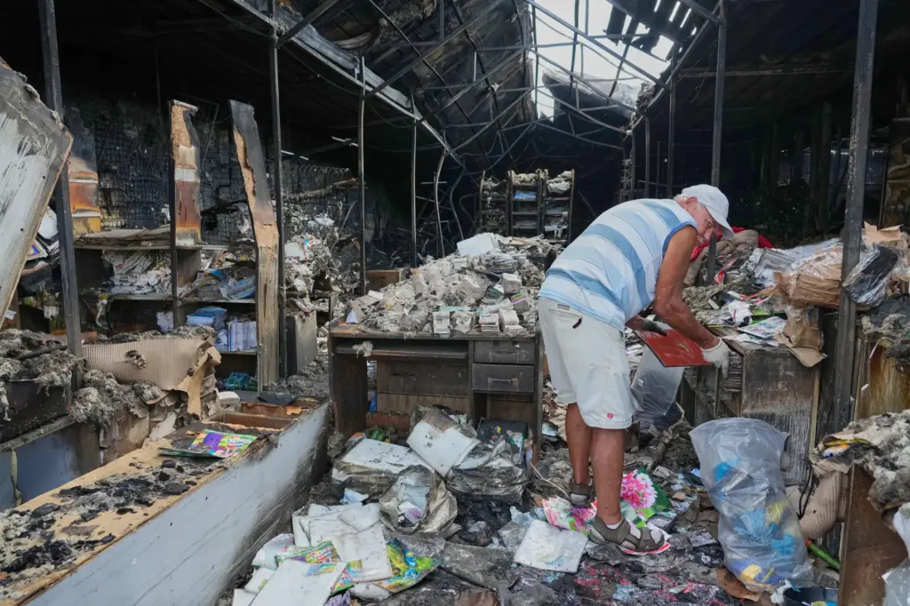FILE – A man searches burned books after a fire...