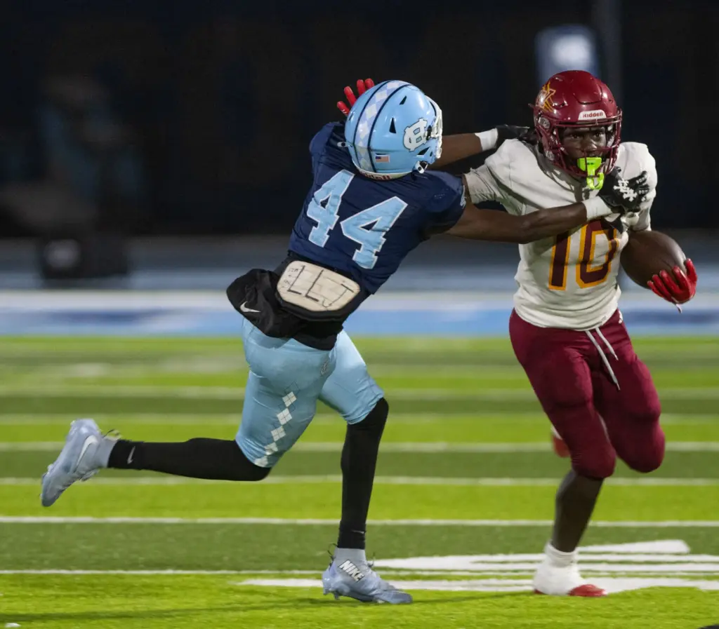 Compton’s Ta’Kai McKnight is stiff armed by Long Beach Wilson’s...