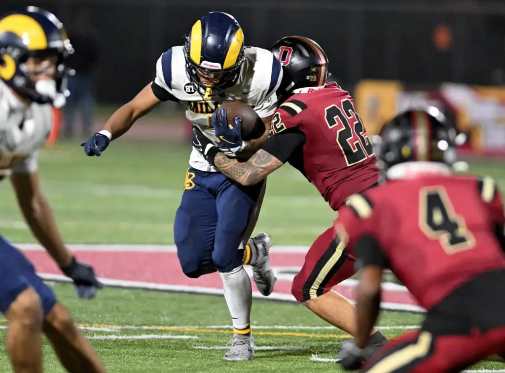 Downey’s Gavin Chapman (22) tackles Millikan Rams Ryan Carter (7)...