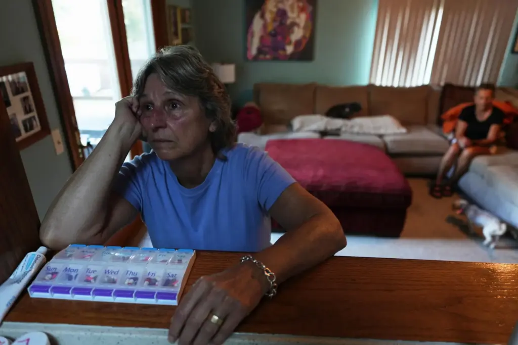 Kate Koubek pauses after talking about her wife's terminal illness in front of a pill organizer.