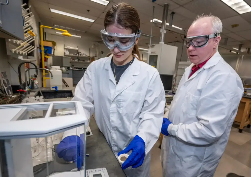 Cal State Fullerton Chemistry Professor Daniel Curtis looks on as...