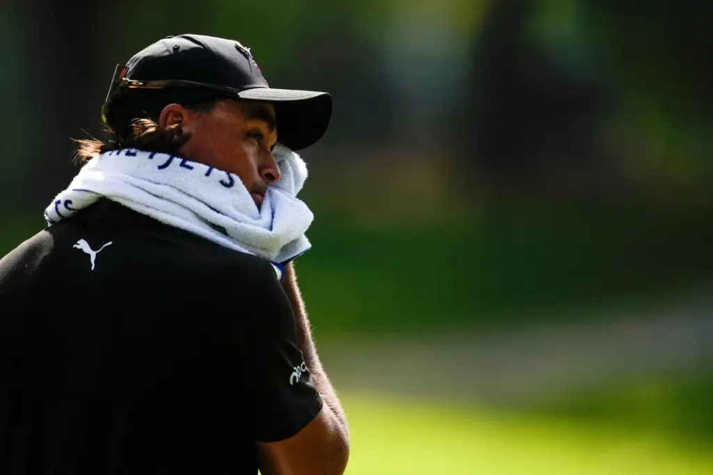 Rickie Fowler wipes his face in the heat.