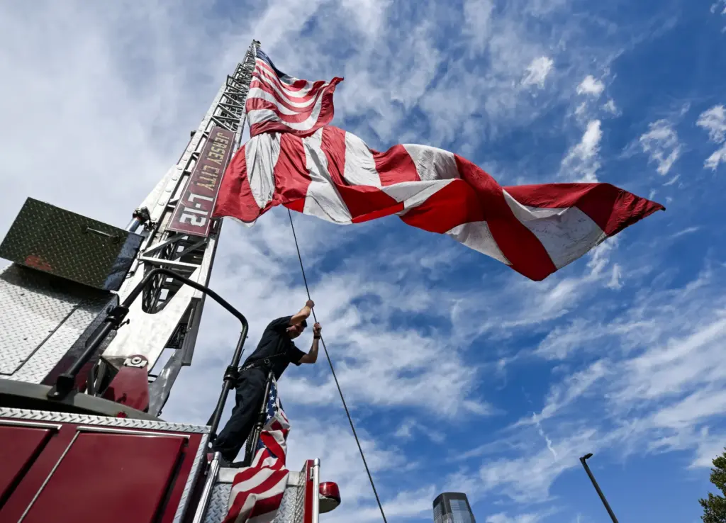 A Jersey City firefighter hoists a flag for a remembrance...