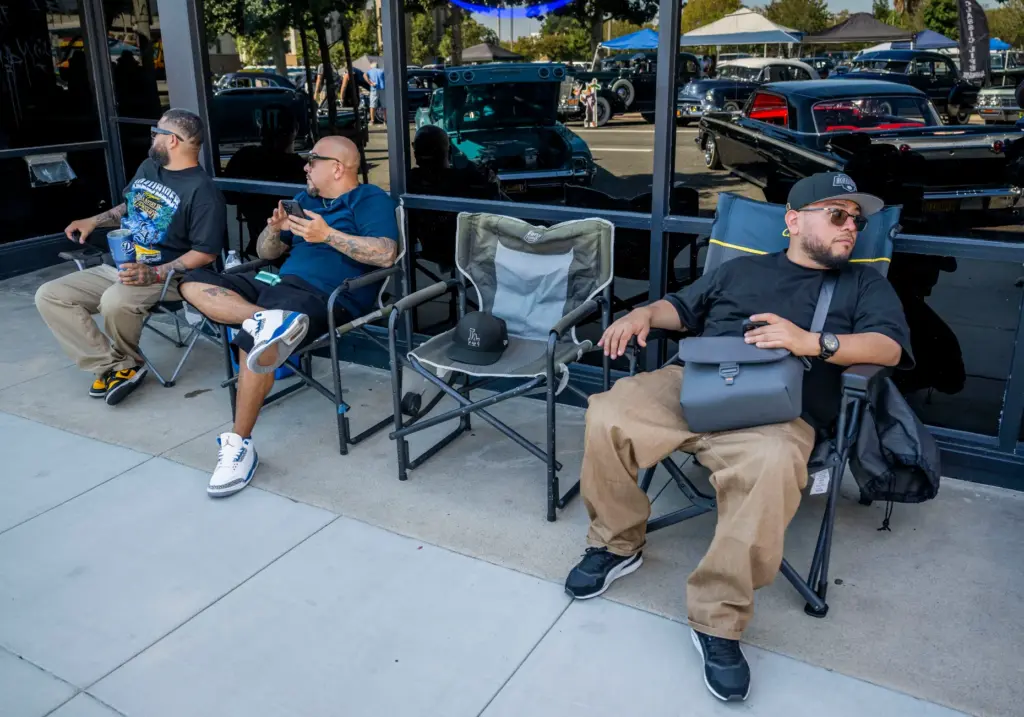 Classic car enthusiasts watch as classic cars drive by during...