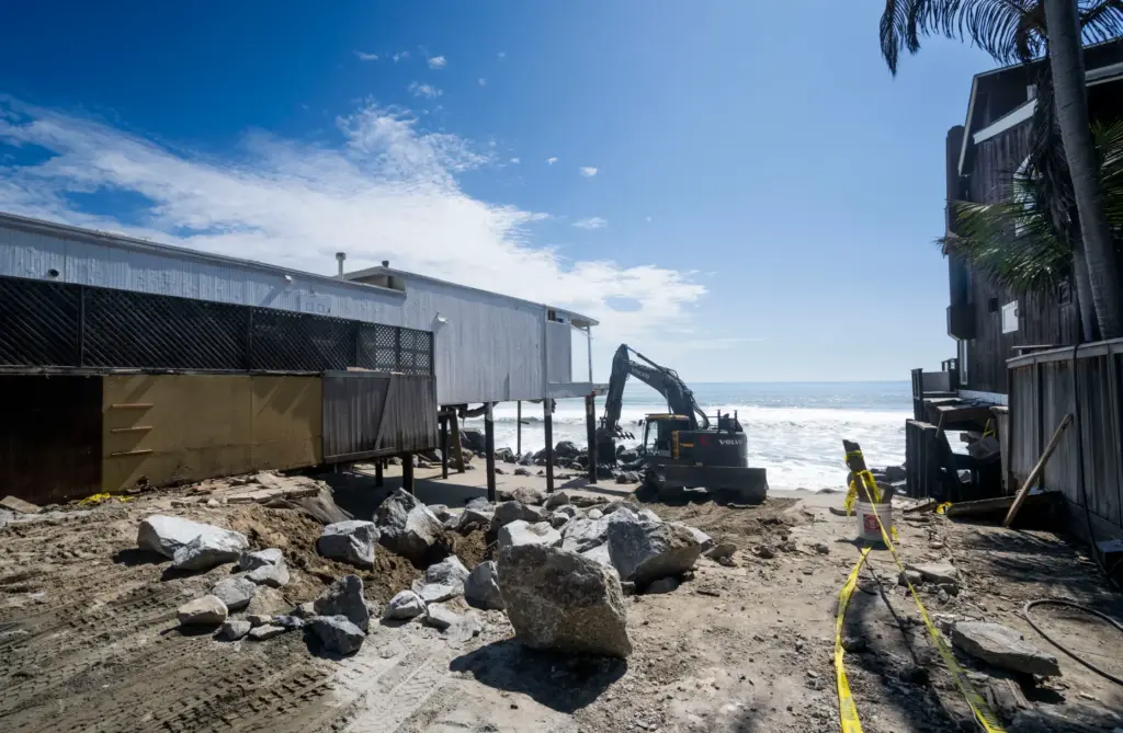 Heavy equipment moves boulders into place to protect homes along...