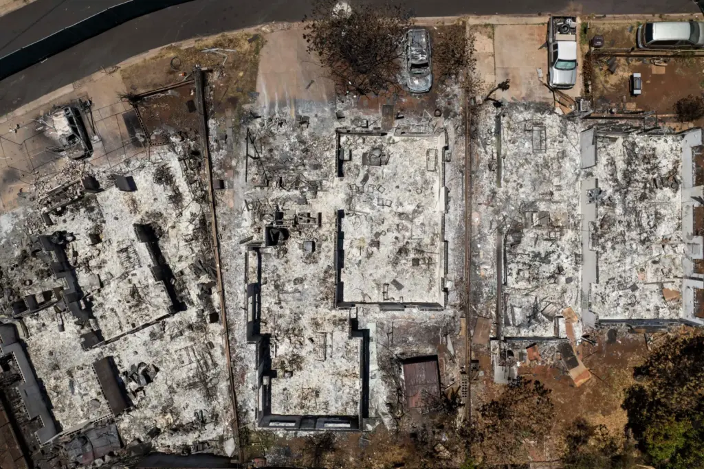 FILE – The remains of homes are visible in the...