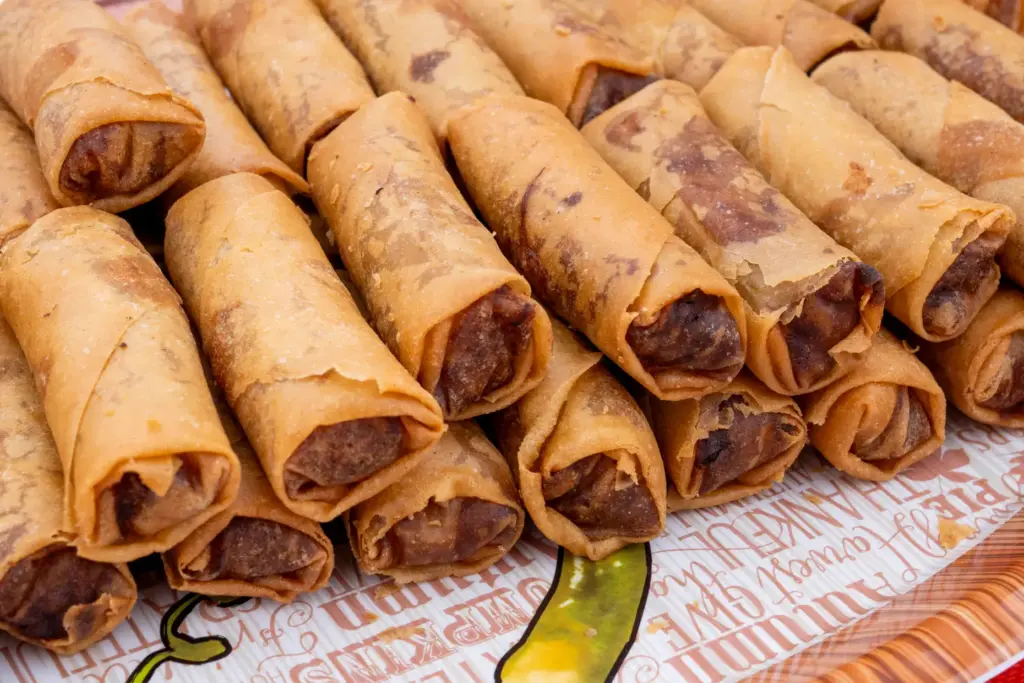 Fried spring rolls fill a plate at a table celebrating...