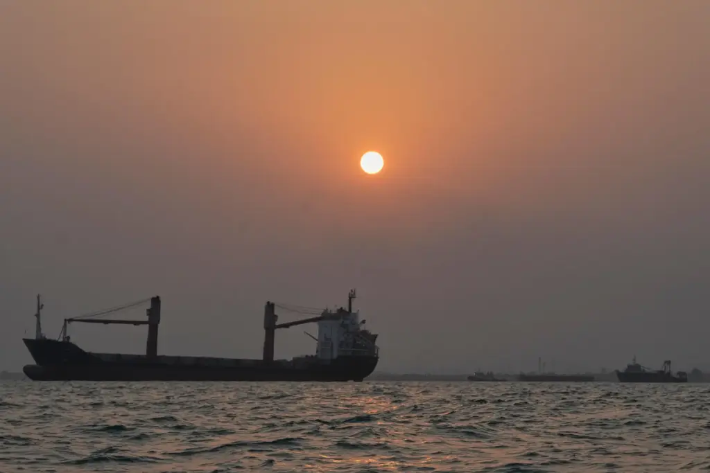 The sun sets over commercial vessels anchored in the Strait...
