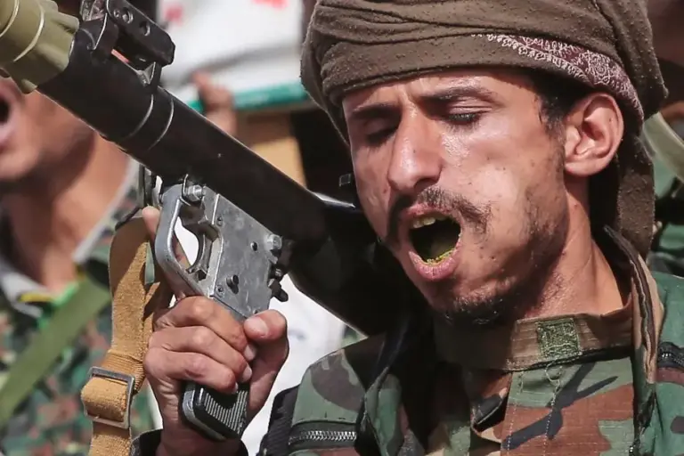 A Yemen’s Houthi rebel chews Qat as he marches during...