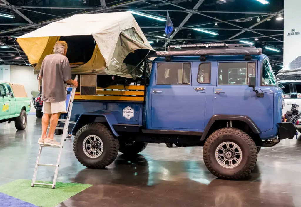 A man examines a 1964 Jeep M677 OVR recreation vehicle...