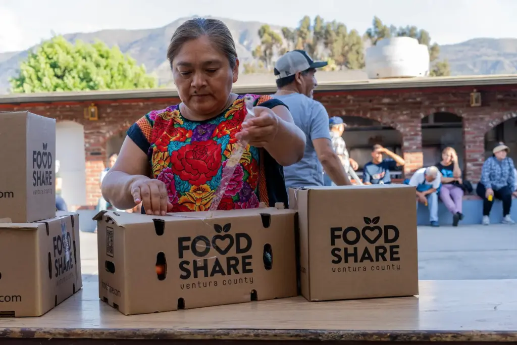Norma Gómez opens boxes of food at a monthly distribution...
