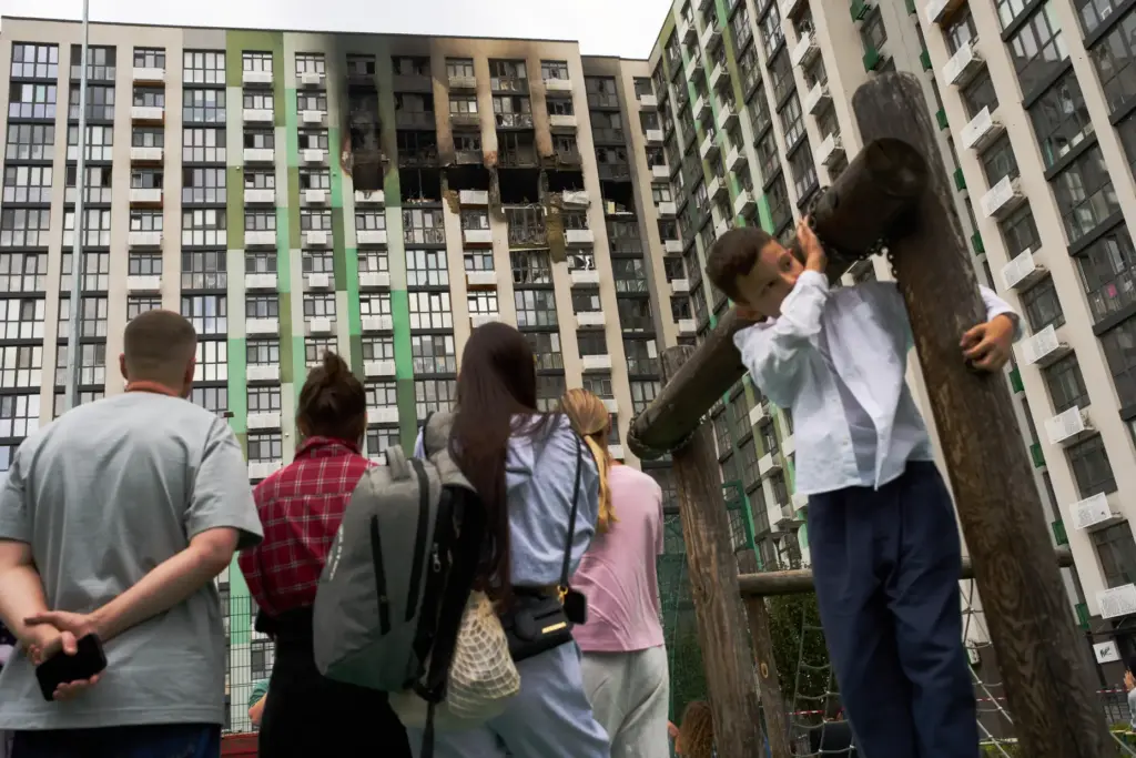 Locals watch as firefighters work after a Russian drone attack struck a residential building in Kyiv.