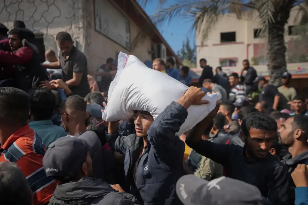 FILE – Palestinians gather to receive bags of flour distributed...