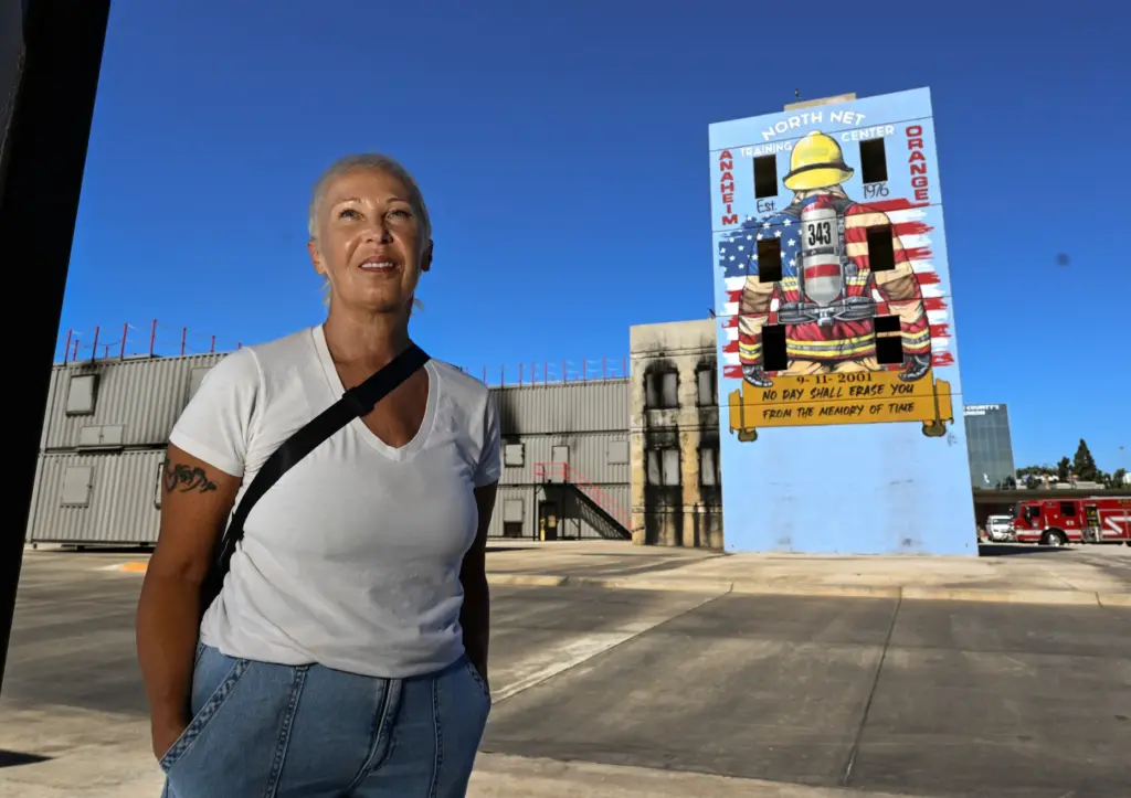 Muralist Rosie Tos near the burn tower that adorns her...