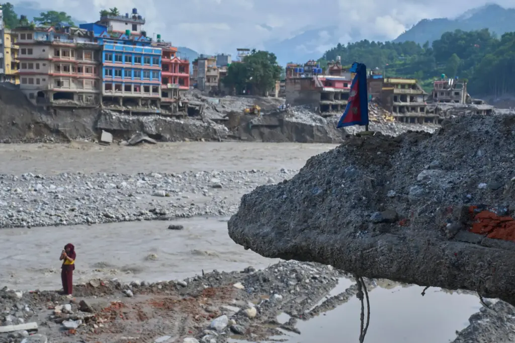 A monk takes photos near a house damaged by flash...