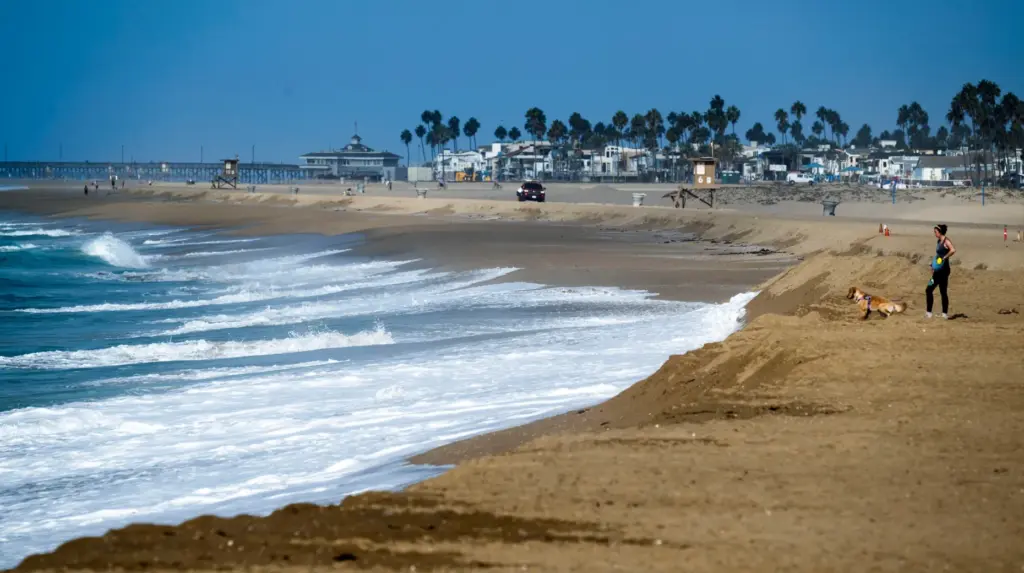 A woman stands on top of a sand berm as...