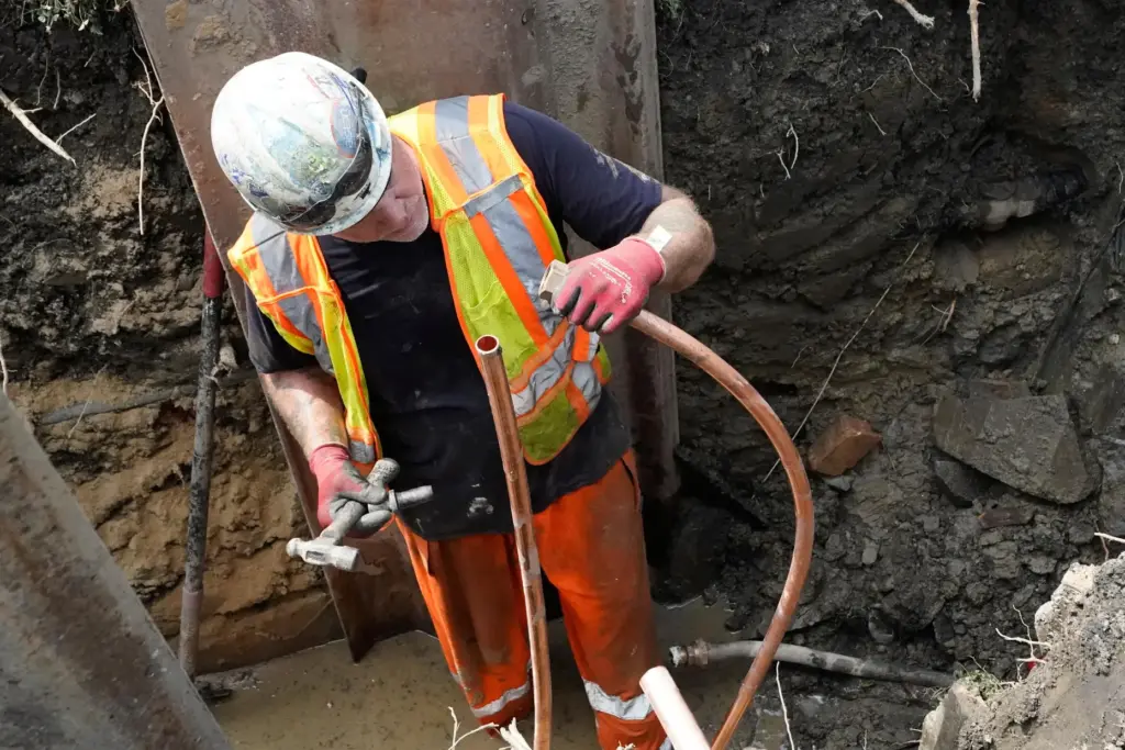 Workers install a copper pipe to replace a lead service...
