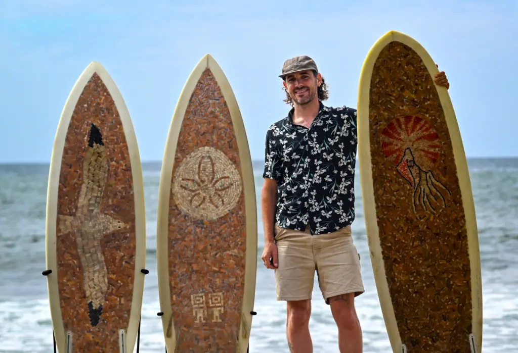 Filmmaker Ben Judkins with surfboards made with cigarette butts collected...