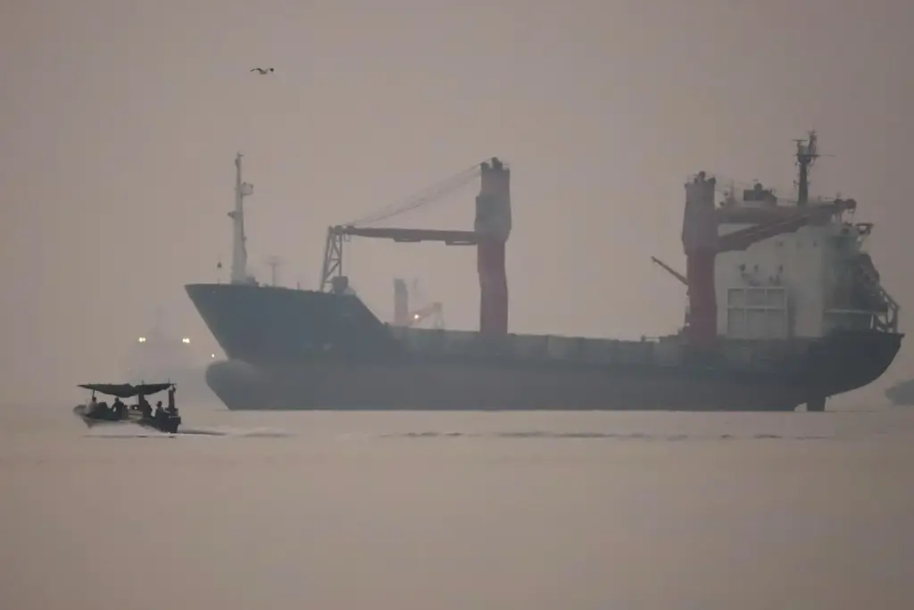 A motorboat passes an anchored cargo ship in the Strait of Hormuz.