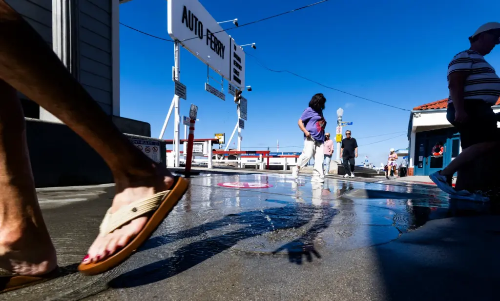People cross a stream of water coming out of a...